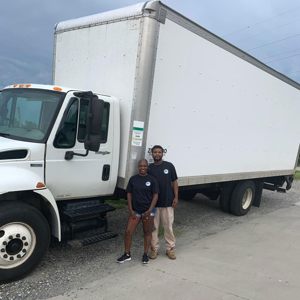 Billy and Shikira standing in front of a freight truck